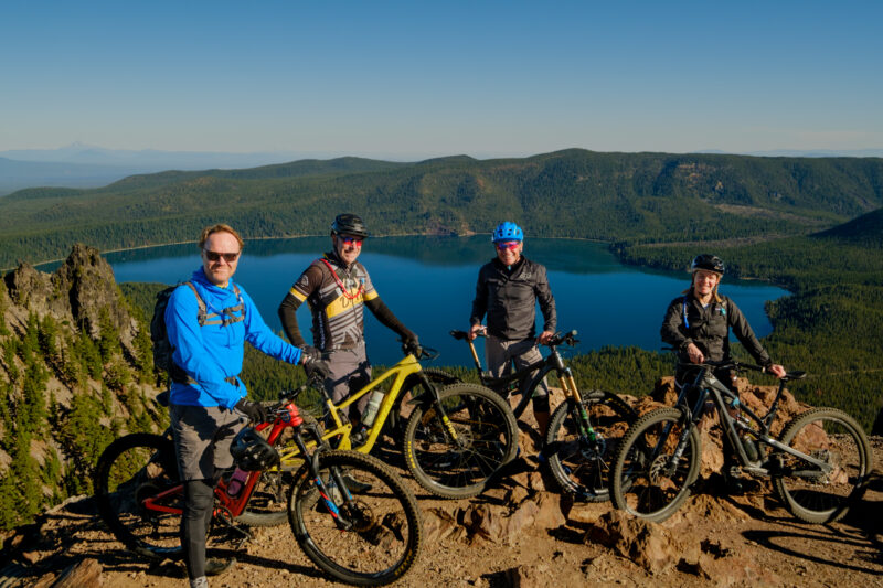 Mountain bikers pose for a picture in front of Paulina Lake. 