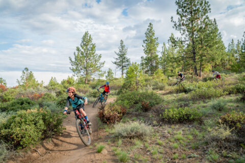 A family rides mountain bikes on trail in Bend, Oregon. 