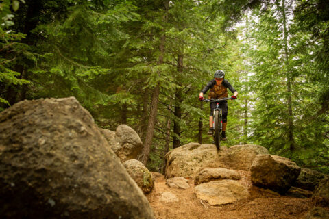 A mountain biker rolls over a rock on Tiddlywinks Trail near Bend, Oregon. 