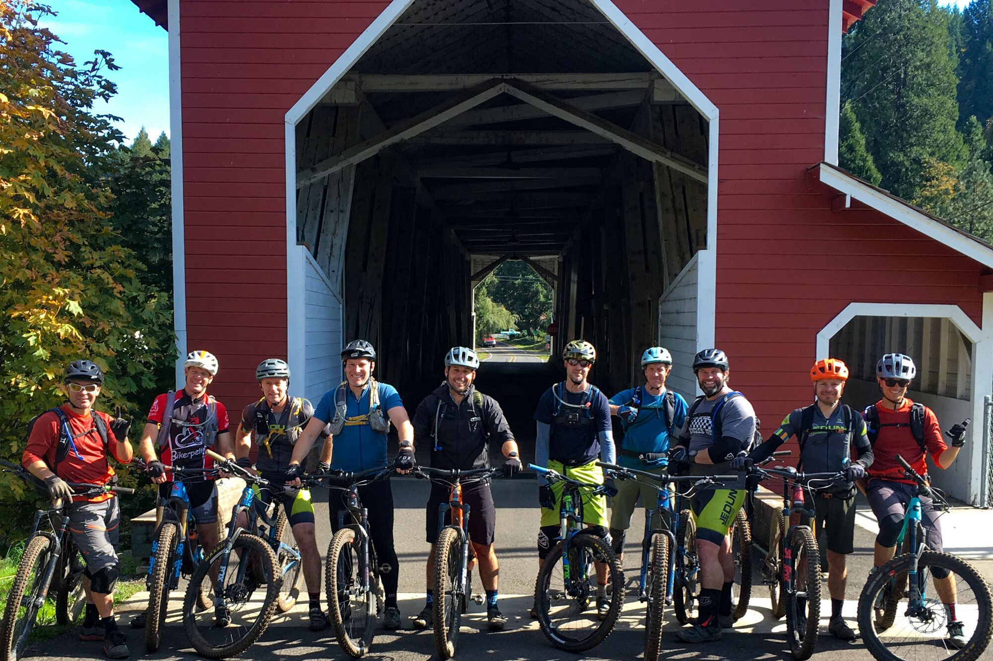 A group of mountain bikers pose at the covered bridge at the base of Alpine Trail in Oakridge, Oregon.