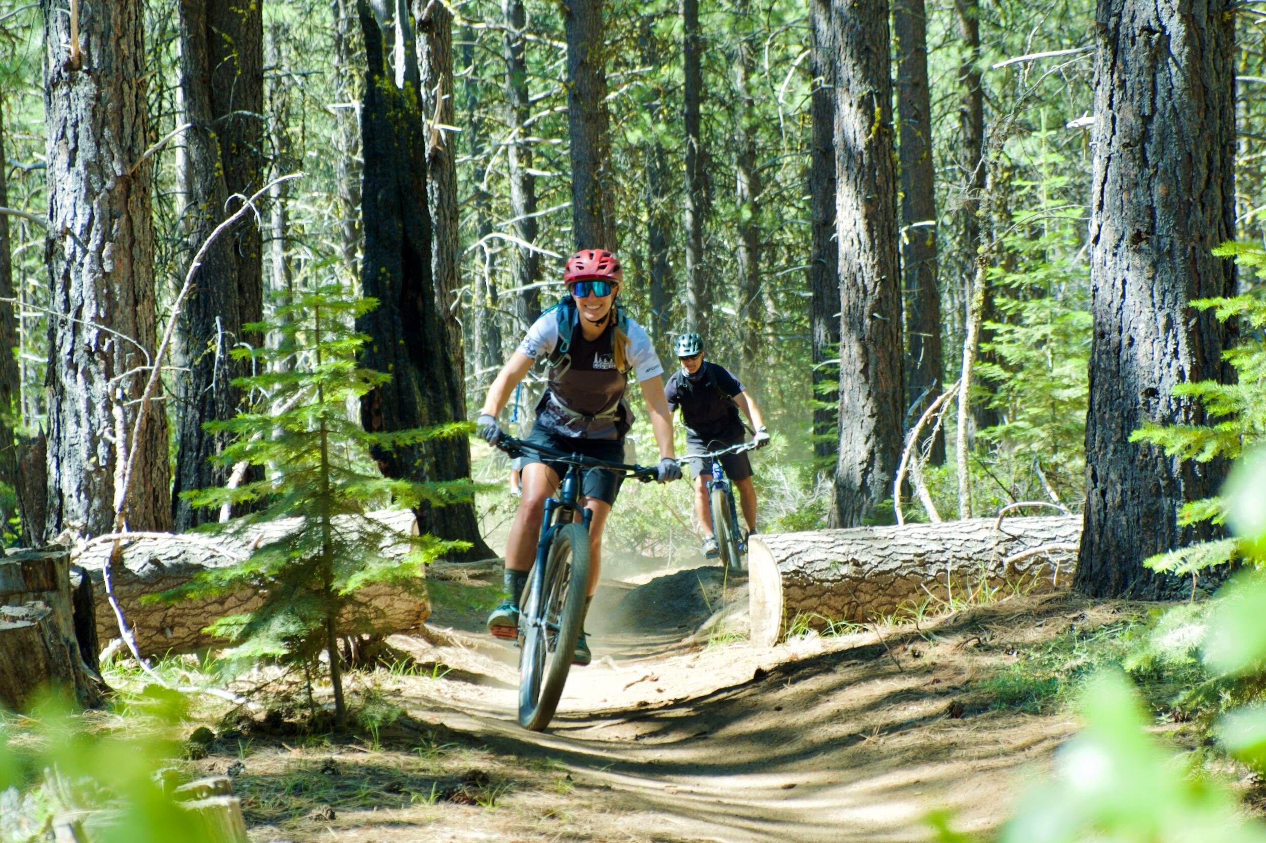 A mountain bike guide leads a client on a single track trail through the forest. 
